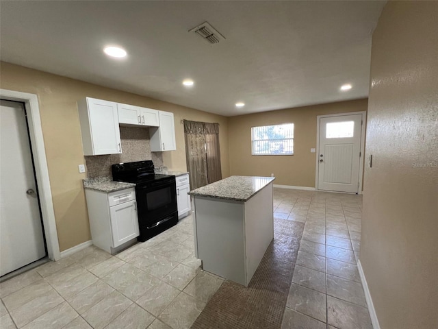 kitchen with white cabinets, backsplash, a center island, and electric range