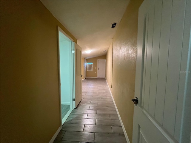 hallway featuring light hardwood / wood-style flooring and vaulted ceiling