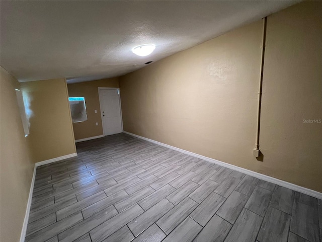 additional living space featuring light hardwood / wood-style flooring and a textured ceiling