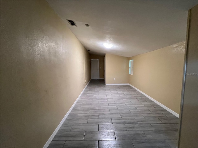 spare room with light wood-type flooring and lofted ceiling