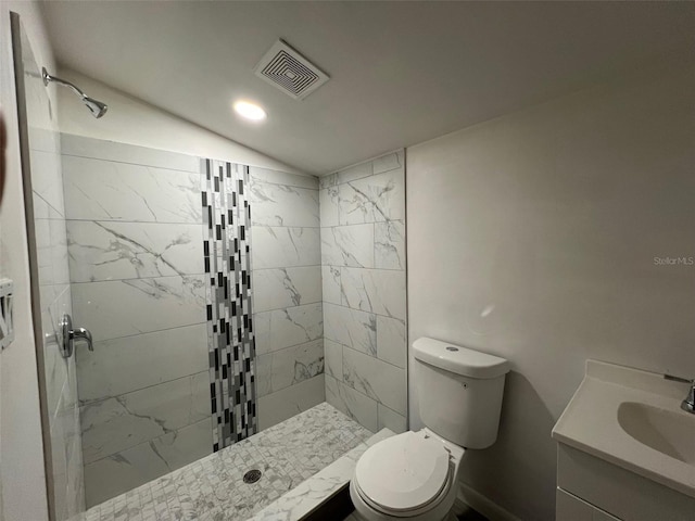 bathroom featuring vanity, toilet, and a tile shower