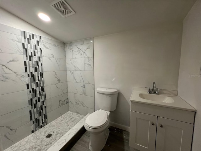 bathroom featuring toilet, vanity, and tiled shower