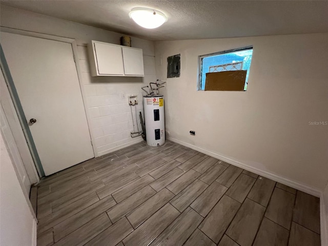 washroom featuring electric water heater, light wood-type flooring, a textured ceiling, cabinets, and electric panel