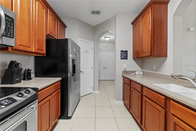 kitchen featuring appliances with stainless steel finishes, light tile patterned floors, and sink