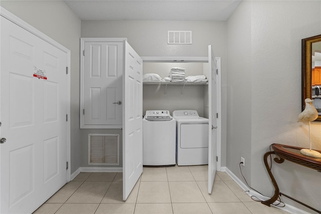 laundry room with independent washer and dryer and light tile patterned flooring