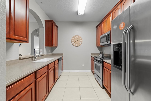 kitchen featuring a textured ceiling, appliances with stainless steel finishes, light tile patterned flooring, and sink