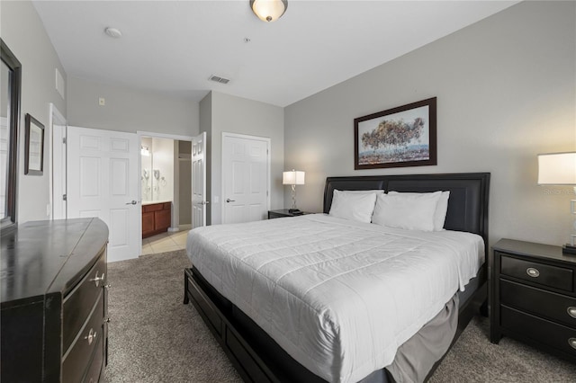 bedroom featuring ensuite bath and light colored carpet