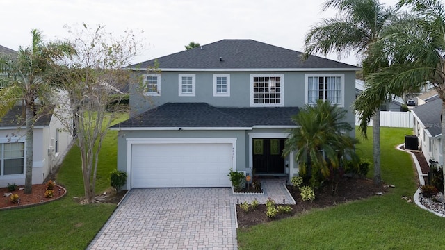 view of front of home featuring a front yard, roof with shingles, stucco siding, cooling unit, and decorative driveway