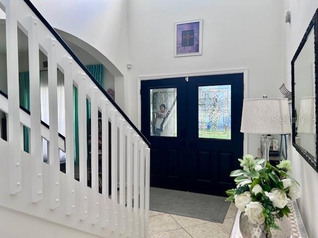 foyer entrance featuring french doors, a high ceiling, and light tile patterned flooring