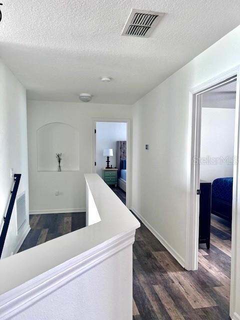 hall featuring dark wood-type flooring and a textured ceiling