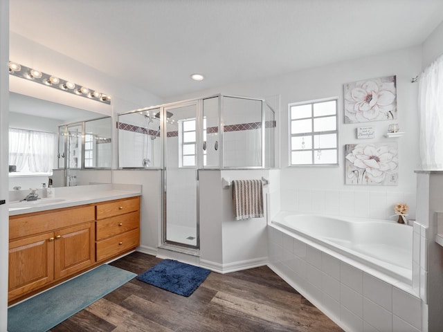 bathroom featuring plus walk in shower, vanity, and wood-type flooring