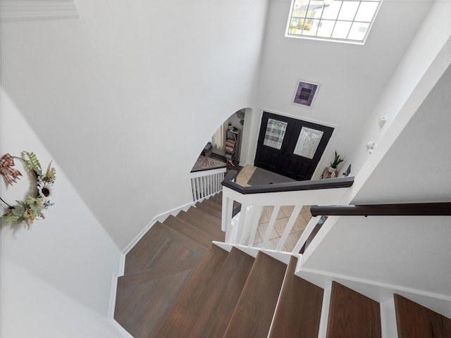 stairs with french doors and a towering ceiling