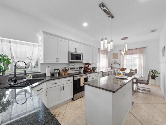 kitchen featuring stainless steel appliances, white cabinetry, hanging light fixtures, and sink