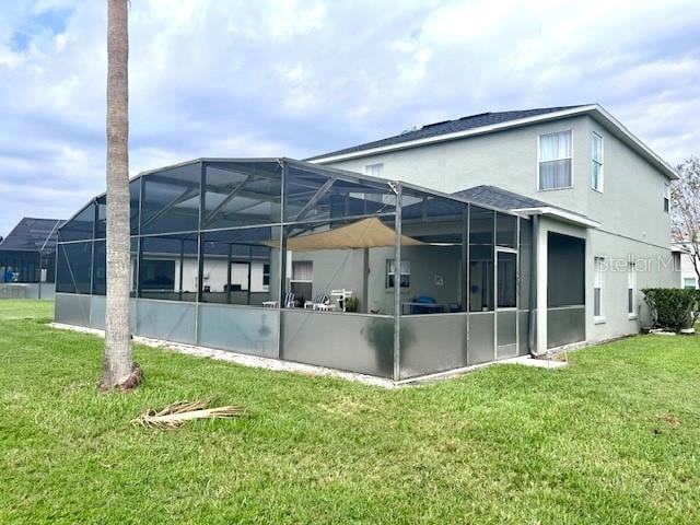 rear view of property featuring a lanai and a lawn