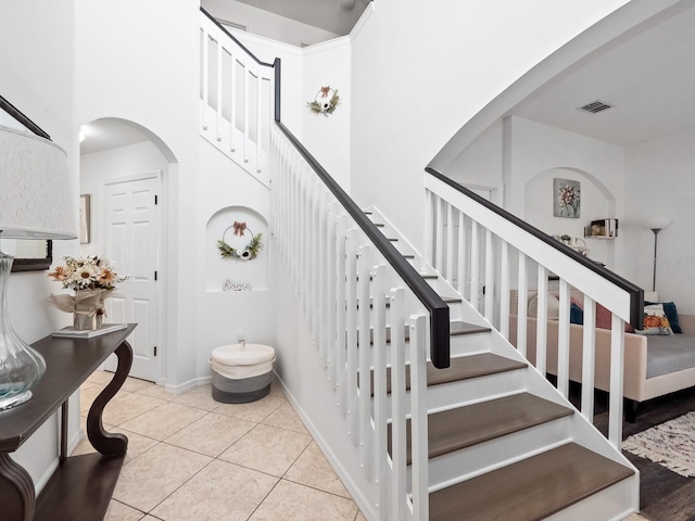 stairway featuring tile patterned floors and a high ceiling