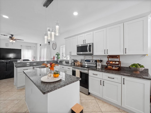 kitchen with a kitchen island, kitchen peninsula, decorative light fixtures, white cabinets, and appliances with stainless steel finishes