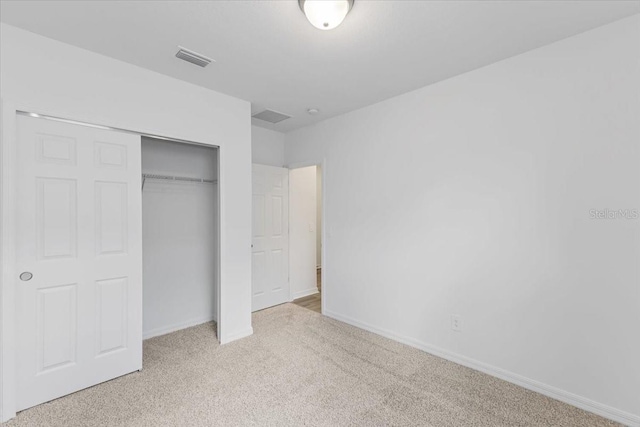 unfurnished bedroom with light carpet and a closet