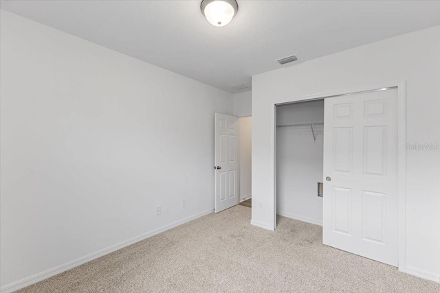 unfurnished bedroom featuring a closet and light colored carpet