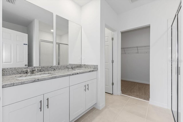 bathroom with tile patterned flooring, vanity, and walk in shower