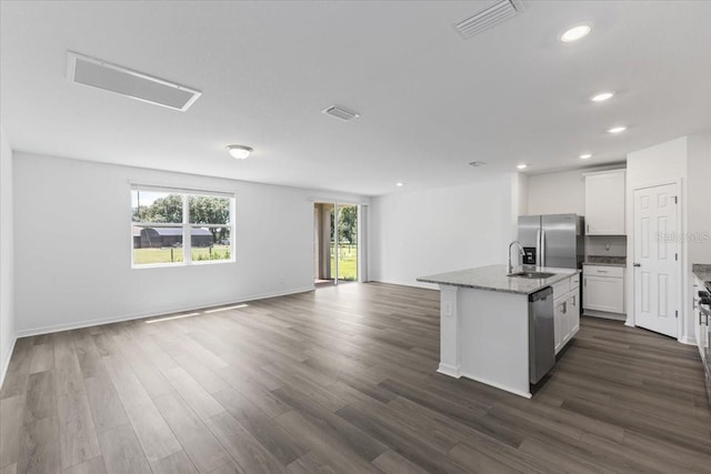 kitchen with light stone countertops, a center island with sink, white cabinets, and stainless steel appliances