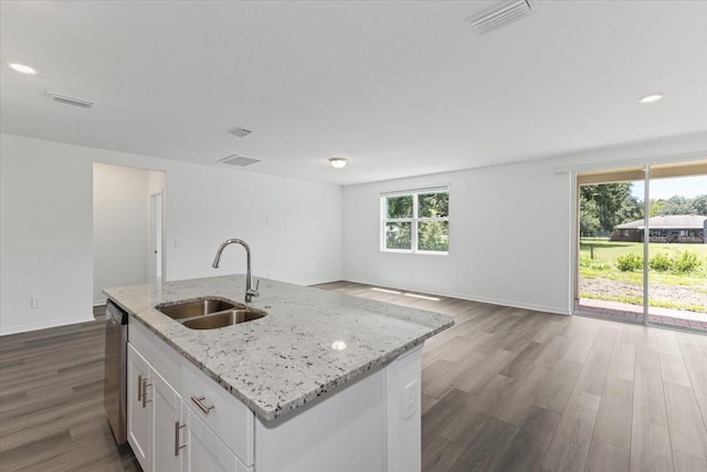 kitchen featuring sink, stainless steel dishwasher, an island with sink, light stone counters, and white cabinetry