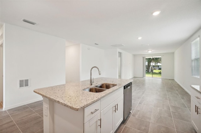 kitchen featuring dishwasher, a center island with sink, sink, light stone counters, and white cabinetry