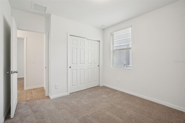 unfurnished bedroom featuring light carpet and a closet