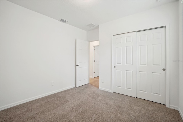 unfurnished bedroom with light carpet and a closet