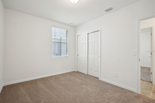 unfurnished bedroom featuring light carpet and a closet