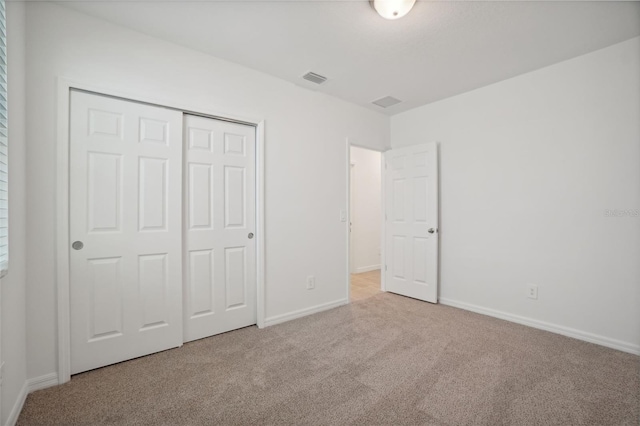 unfurnished bedroom with light carpet and a closet