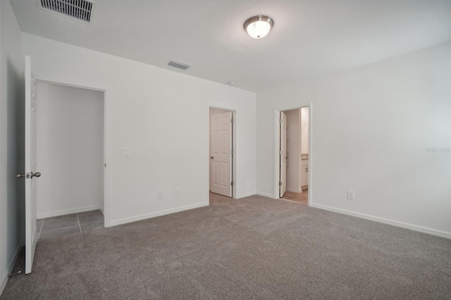 unfurnished bedroom with carpet flooring, ensuite bathroom, and a closet