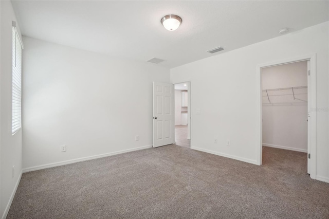 unfurnished bedroom with carpet floors, a spacious closet, and a closet