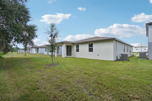 back of house with central AC unit and a lawn