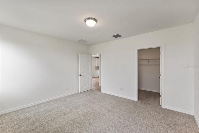 unfurnished bedroom featuring light colored carpet, a spacious closet, and a closet