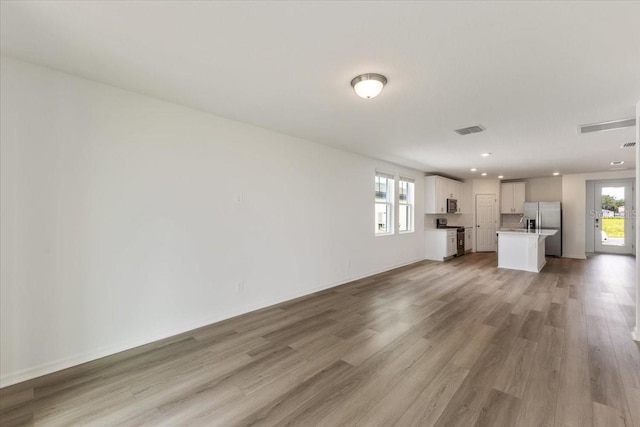 unfurnished living room featuring a wealth of natural light and light hardwood / wood-style flooring