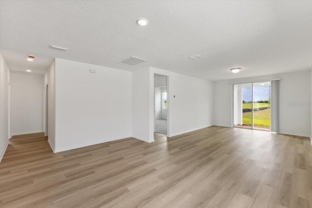 unfurnished room featuring a textured ceiling and light hardwood / wood-style flooring