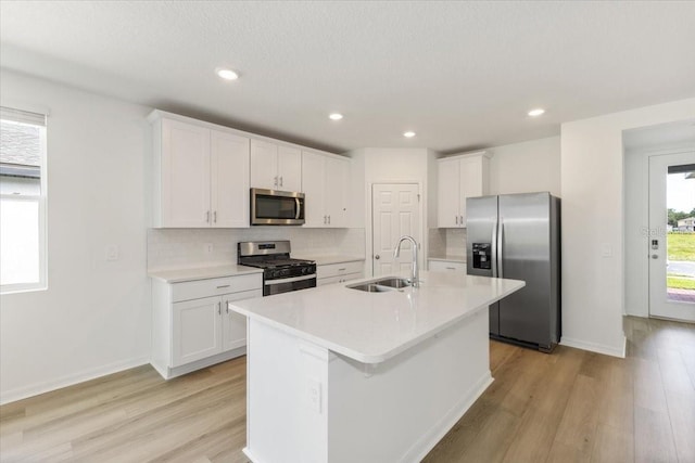 kitchen with white cabinetry, sink, stainless steel appliances, and a center island with sink