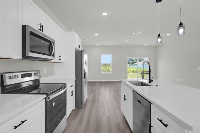 kitchen featuring pendant lighting, stainless steel appliances, light hardwood / wood-style floors, white cabinets, and sink