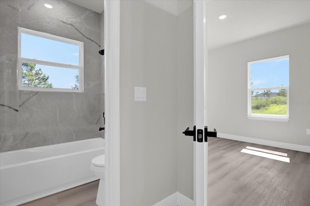 bathroom featuring toilet, tiled shower / bath, and wood-type flooring