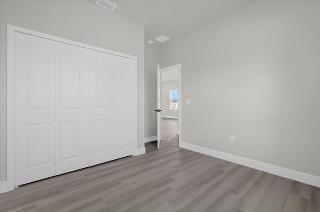 unfurnished bedroom featuring visible vents, baseboards, wood finished floors, and a closet