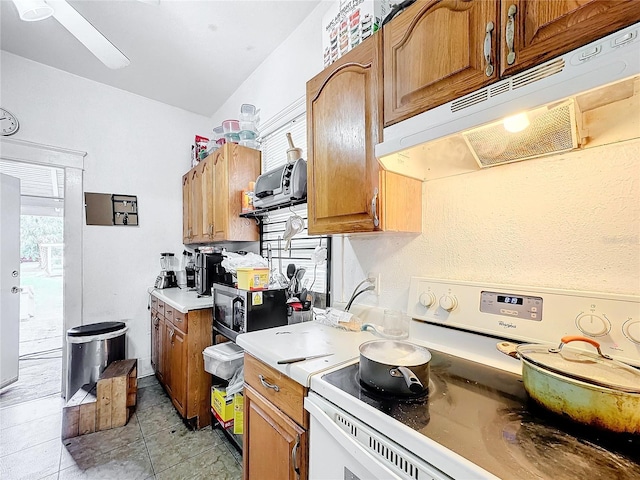 kitchen featuring vaulted ceiling, light tile patterned flooring, and white stove