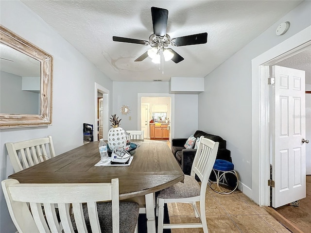 tiled dining area with ceiling fan and a textured ceiling