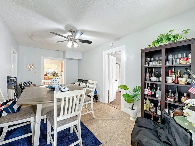 tiled dining space with ceiling fan and a textured ceiling