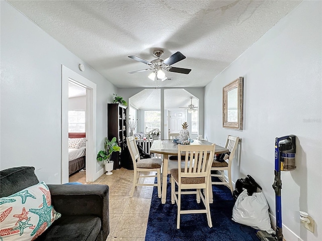 tiled dining space with ceiling fan and a textured ceiling