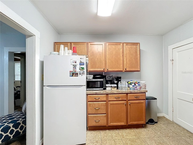 kitchen featuring light tile patterned floors, white refrigerator, and crown molding