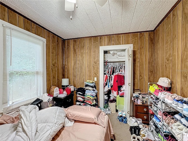 bedroom featuring carpet floors, wood walls, a closet, and ceiling fan