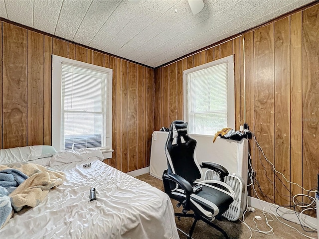 bedroom featuring multiple windows, wooden walls, and ceiling fan