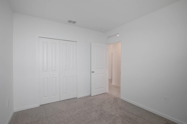 unfurnished bedroom with light carpet and a closet