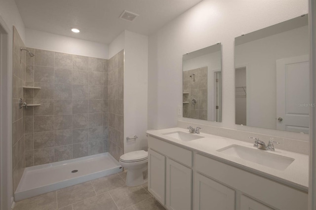 bathroom with a tile shower, vanity, toilet, and tile patterned floors