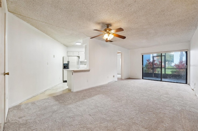 unfurnished living room featuring ceiling fan, light colored carpet, and a textured ceiling